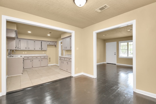 kitchen featuring gray cabinetry, sink, a textured ceiling, and light wood-type flooring