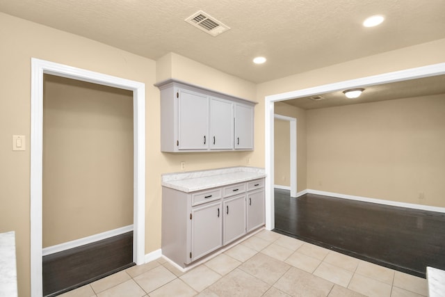 kitchen with gray cabinets, light tile patterned floors, and a textured ceiling