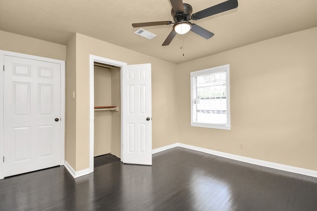 unfurnished bedroom featuring ceiling fan, dark hardwood / wood-style flooring, a textured ceiling, and a closet