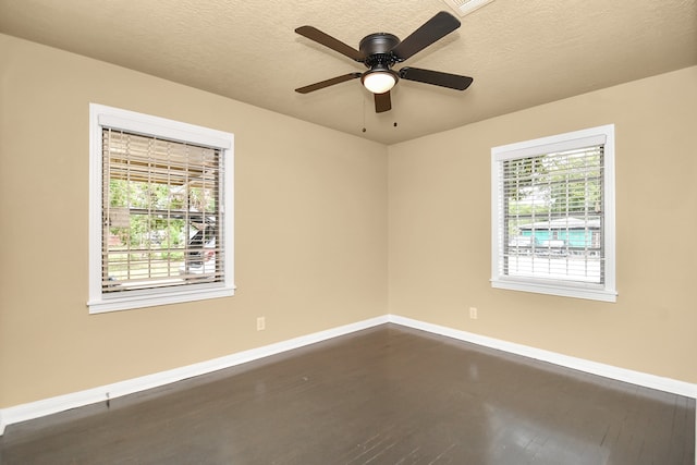 unfurnished room with a wealth of natural light, dark wood-type flooring, and a textured ceiling