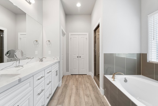 bathroom featuring plus walk in shower, vanity, and hardwood / wood-style floors