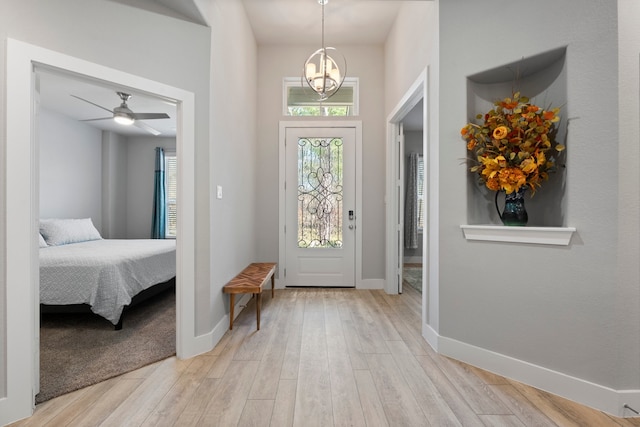 foyer entrance featuring ceiling fan with notable chandelier and light hardwood / wood-style flooring