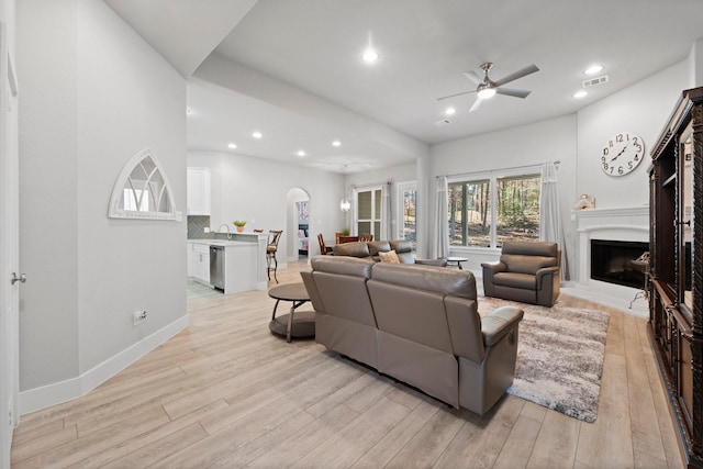 63 Shetland Ln, Coldspring, TX 77331 - living room with a fireplace with raised hearth, light wood-style floors, ceiling fan, recessed lighting, and arched walkways