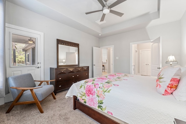 carpeted bedroom with ceiling fan and a raised ceiling