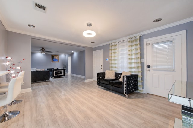 sitting room featuring light wood-type flooring, ceiling fan, and crown molding