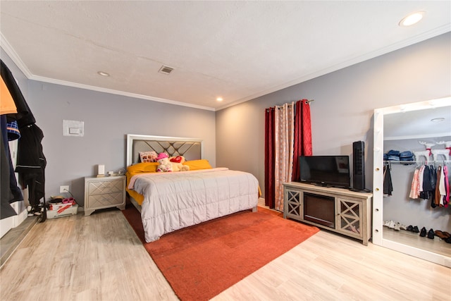 bedroom with hardwood / wood-style floors, crown molding, and a closet