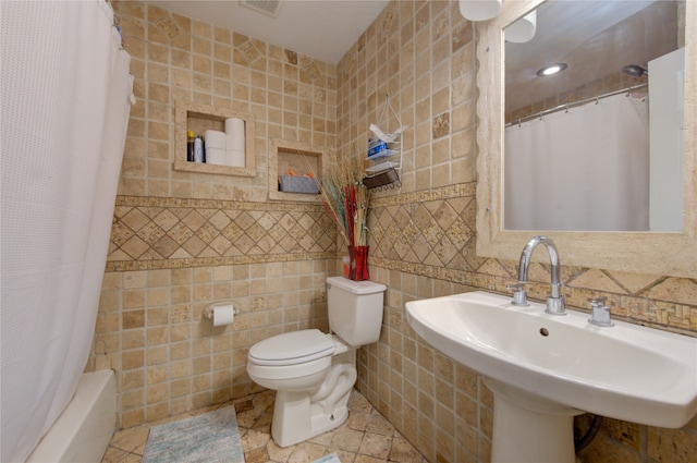 full bathroom with tile walls, shower / bath combo with shower curtain, toilet, and sink