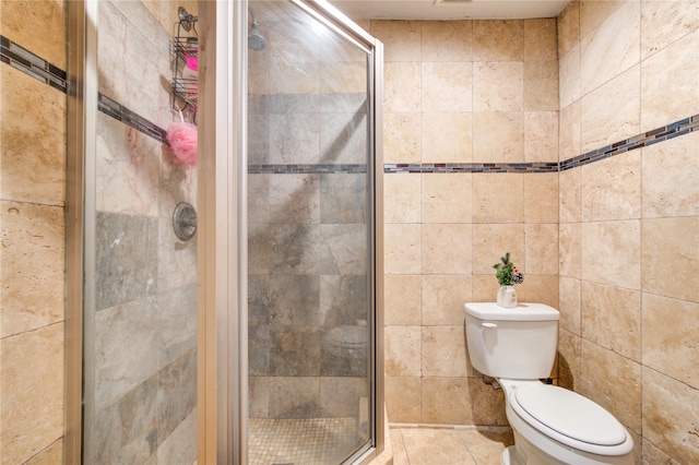 bathroom featuring toilet, tile patterned floors, tile walls, and a shower with door