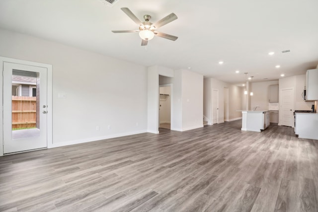 unfurnished living room with ceiling fan, sink, and light hardwood / wood-style floors