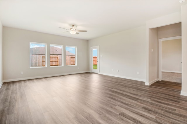 spare room with dark wood-style floors, ceiling fan, and baseboards