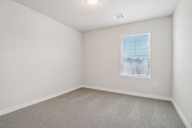 carpeted empty room featuring visible vents and baseboards