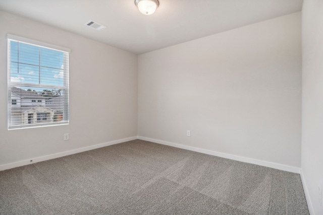 carpeted spare room featuring baseboards and visible vents