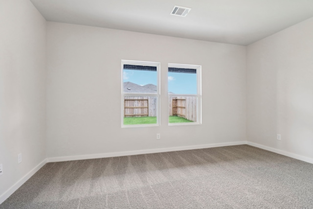 empty room featuring carpet floors, visible vents, and baseboards