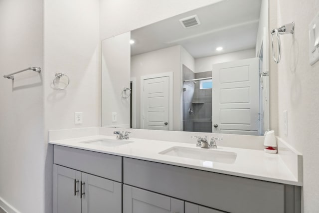 full bathroom with double vanity, a stall shower, a sink, and visible vents