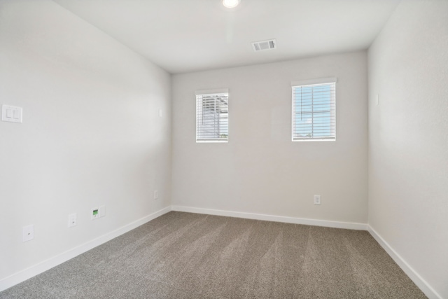 spare room featuring carpet, visible vents, and baseboards