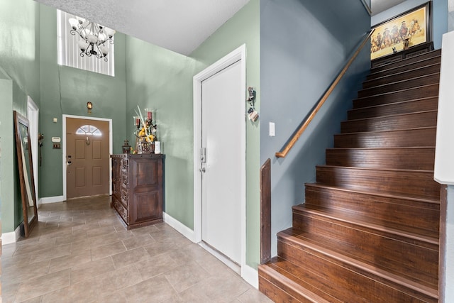 tiled foyer entrance with a notable chandelier and a textured ceiling