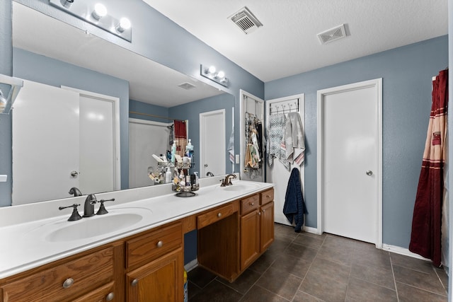 bathroom with curtained shower, vanity, a textured ceiling, and tile patterned floors