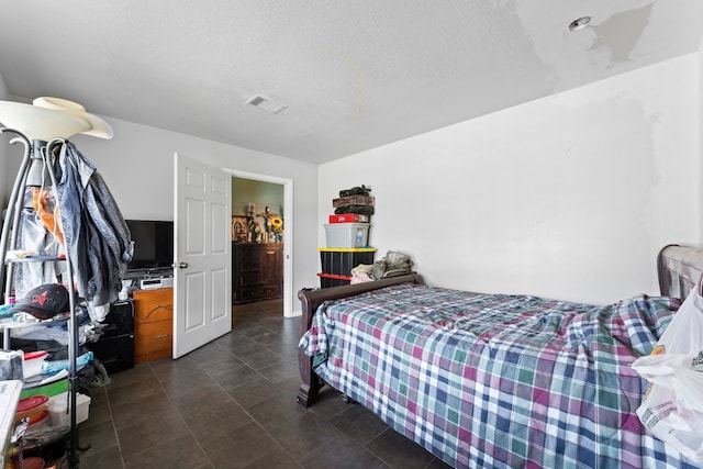 bedroom with a textured ceiling and dark tile patterned floors