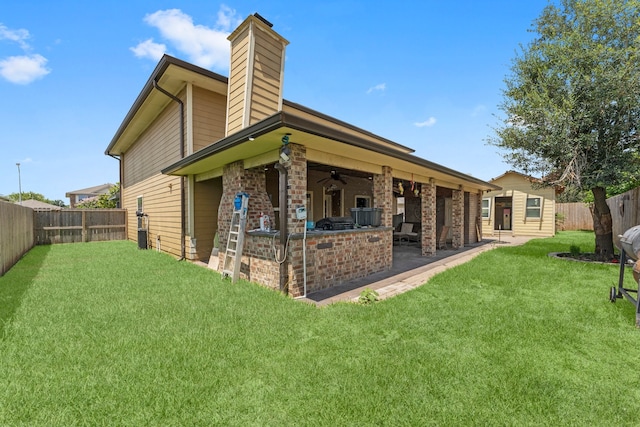 rear view of property with a patio area, ceiling fan, a yard, and exterior kitchen