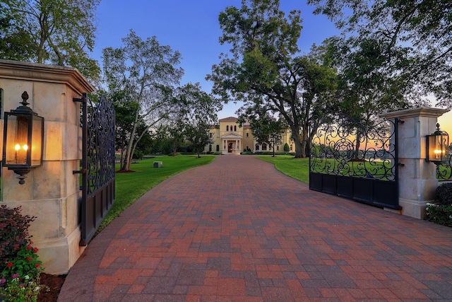 gate at dusk featuring a lawn