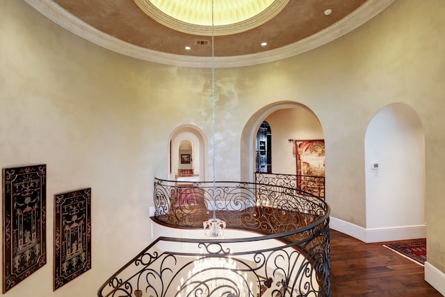 hallway with hardwood / wood-style flooring, ornamental molding, and a towering ceiling