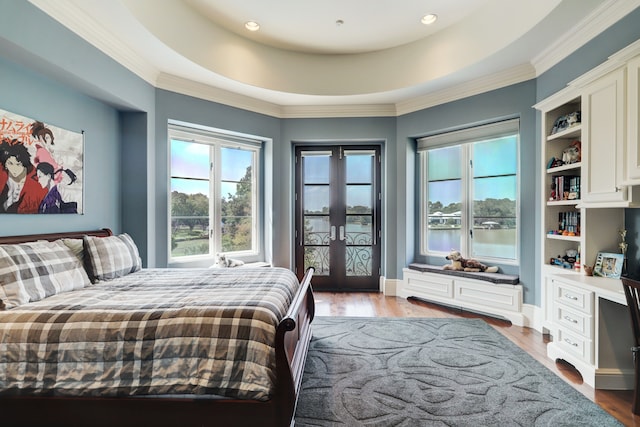 bedroom featuring ornamental molding, light hardwood / wood-style floors, and a raised ceiling