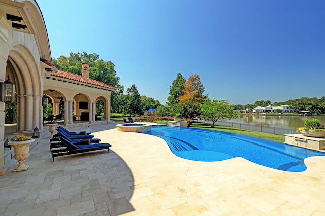 view of pool featuring an in ground hot tub, a water view, and a patio area