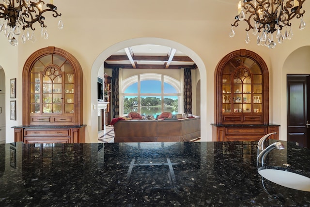 interior space featuring beam ceiling, dark stone counters, sink, and coffered ceiling