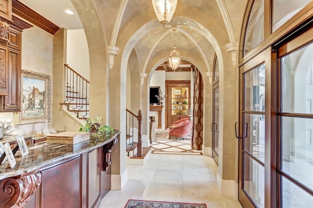 hall with ornamental molding, vaulted ceiling, light tile patterned floors, and ornate columns