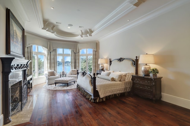 bedroom with ornamental molding, dark hardwood / wood-style flooring, and a tray ceiling