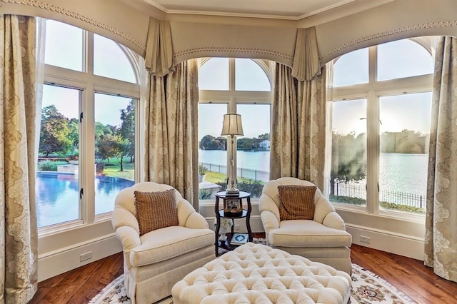 sitting room featuring hardwood / wood-style floors, a water view, and crown molding