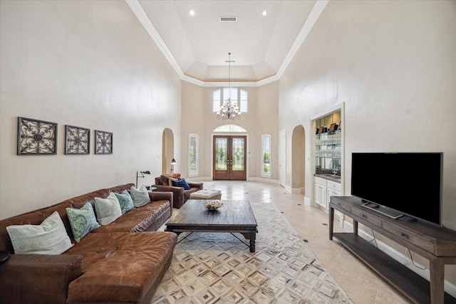 tiled living room featuring crown molding, a towering ceiling, an inviting chandelier, and french doors