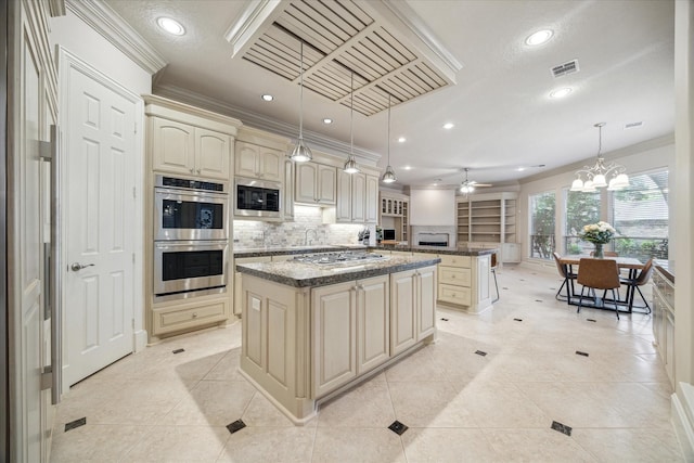 kitchen with a kitchen island, appliances with stainless steel finishes, pendant lighting, and cream cabinets