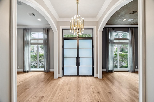 foyer entrance with light hardwood / wood-style floors, french doors, a healthy amount of sunlight, and a notable chandelier