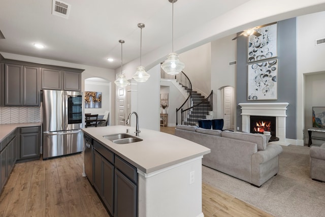 kitchen featuring a center island with sink, appliances with stainless steel finishes, sink, and light hardwood / wood-style flooring