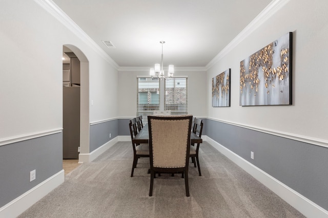 carpeted dining area with ornamental molding and a notable chandelier