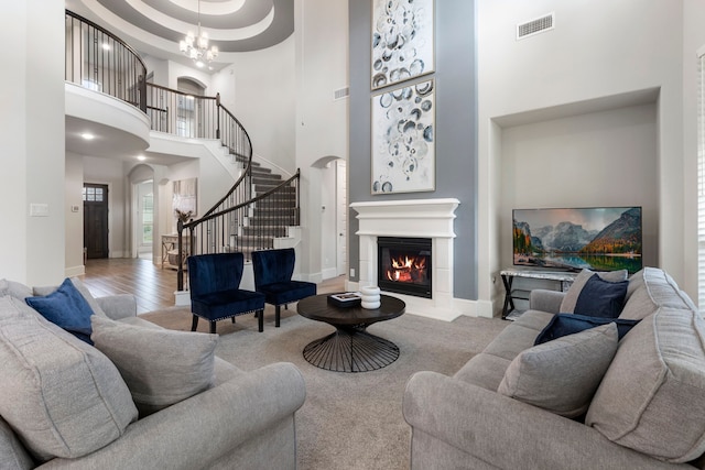 living room with a high ceiling, light hardwood / wood-style floors, and a notable chandelier