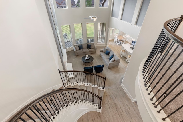 stairs featuring hardwood / wood-style flooring, ceiling fan, and a towering ceiling