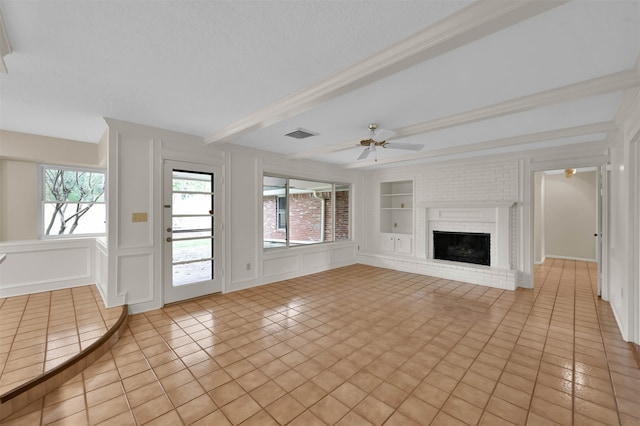 unfurnished living room featuring a brick fireplace, built in shelves, light tile patterned floors, beamed ceiling, and ceiling fan