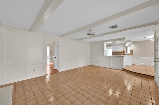 unfurnished living room featuring ceiling fan, sink, light tile patterned flooring, and beam ceiling