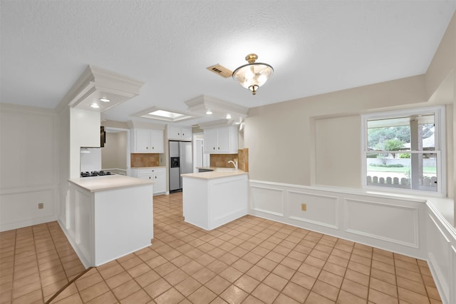 kitchen with stainless steel fridge with ice dispenser, white cabinetry, light tile patterned floors, and kitchen peninsula