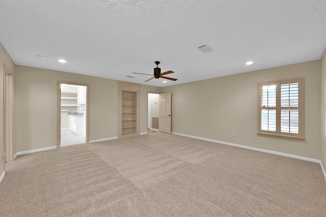 unfurnished bedroom featuring ceiling fan, light carpet, and a walk in closet