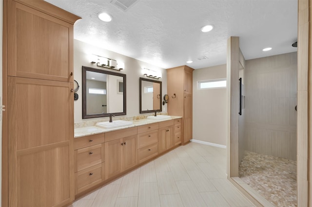 bathroom with a shower, vanity, and a textured ceiling