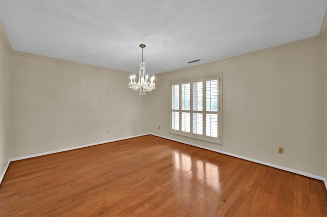 spare room featuring a notable chandelier, light hardwood / wood-style floors, and crown molding