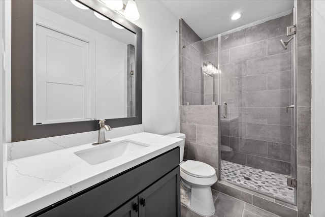 bathroom featuring tile patterned flooring, vanity, toilet, and a shower with shower door