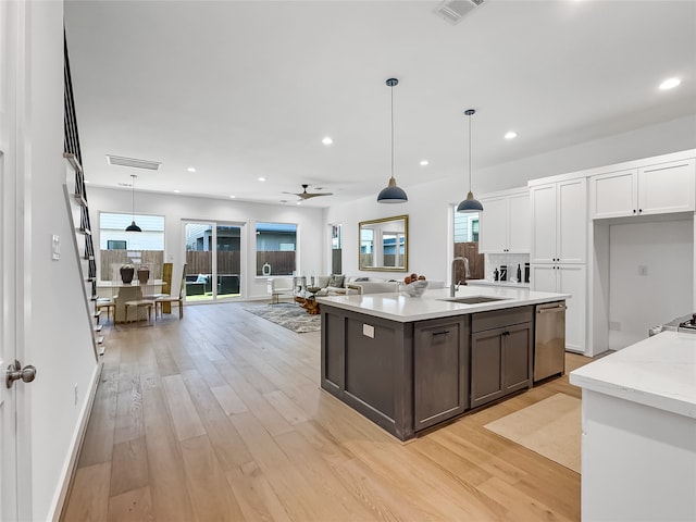 kitchen with white cabinets, light wood-type flooring, decorative light fixtures, and sink