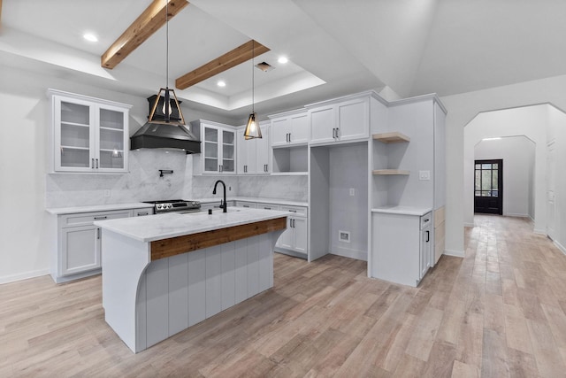 kitchen with light hardwood / wood-style flooring, an island with sink, and white cabinets