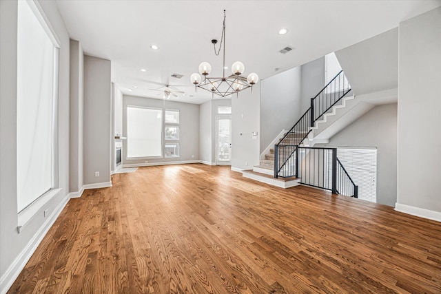 unfurnished living room featuring hardwood / wood-style floors and ceiling fan with notable chandelier