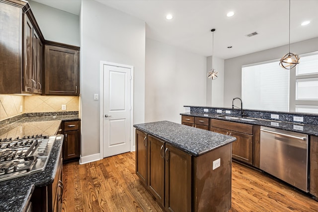 kitchen with dark hardwood / wood-style flooring, sink, a kitchen island, appliances with stainless steel finishes, and decorative light fixtures