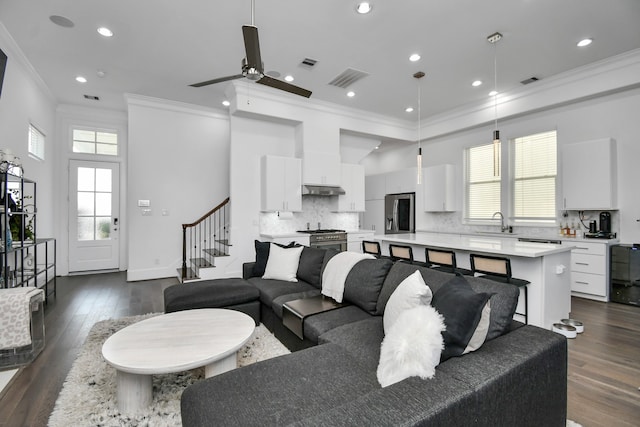 living room with ornamental molding, ceiling fan, sink, and dark hardwood / wood-style floors